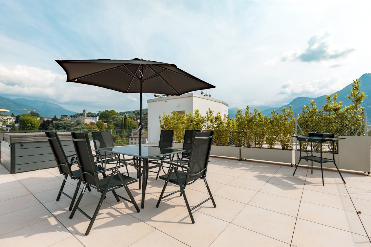 Sunny terrace with furniture, umbrella, and mountain views. Ideal for outdoor relaxation.